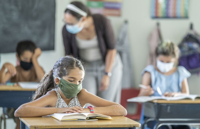 12 year old girl wearing a reusable, protective face mask in classroom while working on school work at her desk. (Foto: Getty Images)