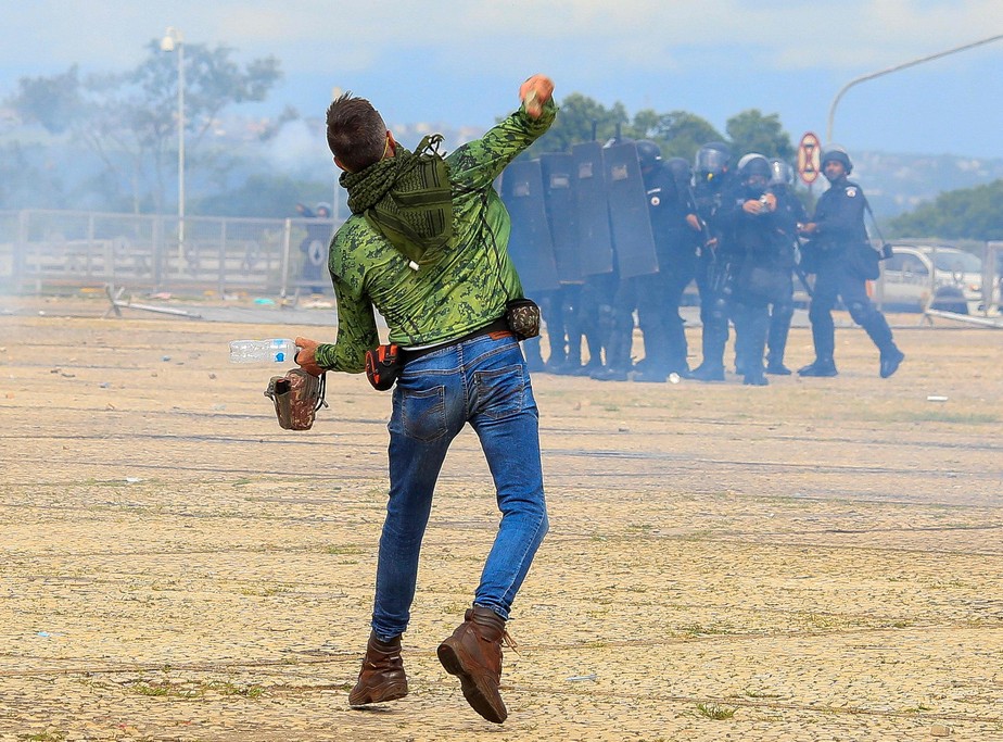 apoiador do ex-presidente brasileiro Jair Bolsonaro atira pedras nas forças de segurança durante confrontos fora do Palácio Presidencial do Planalto, em Brasília