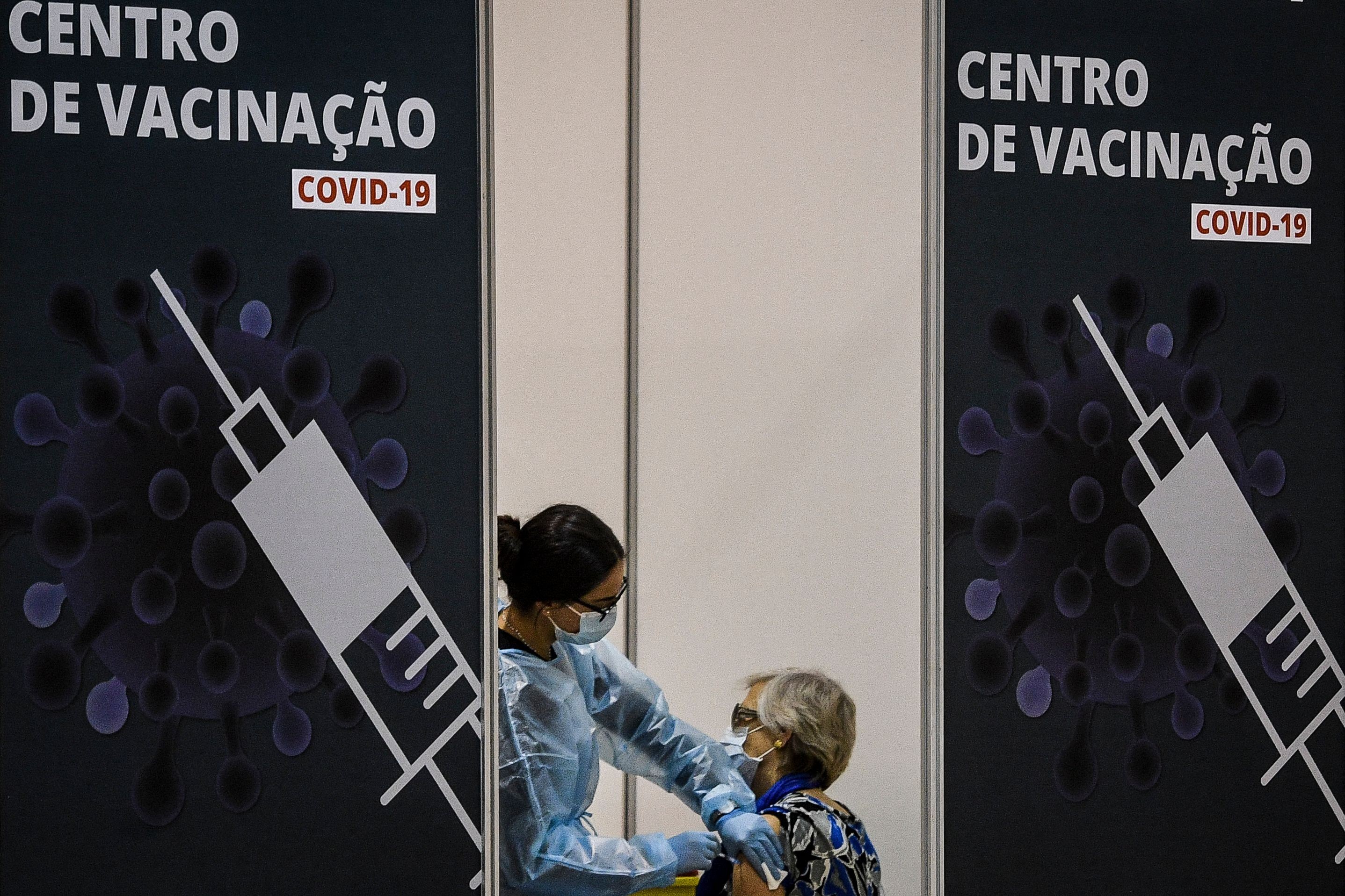 Profissional do Serviço Nacional de Saúde aplica vacina contra a Covid-19 em mulher em Lisboa em 2021