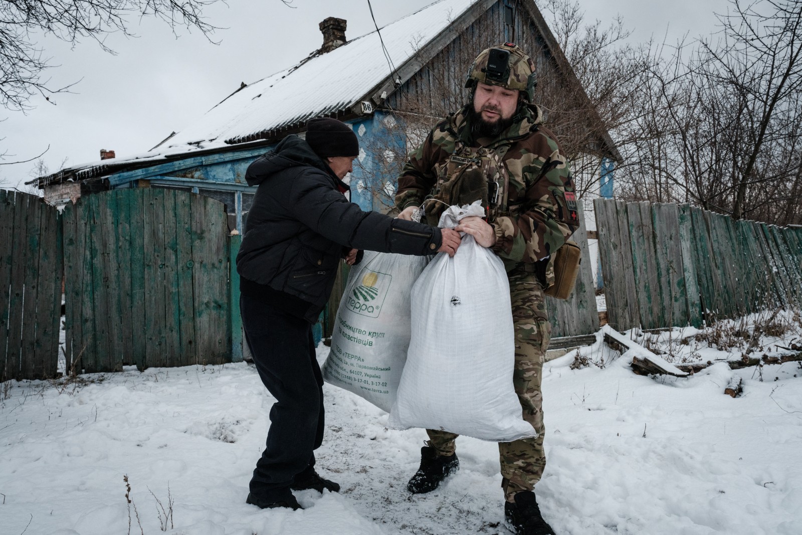 O voluntário Yaroslav Mudryi, de 38 anos, ajuda Grigoriy a evacuar um lugarejo em Chasiv Yar  — Foto: YASUYOSHI CHIBA / AFP - 15/022023