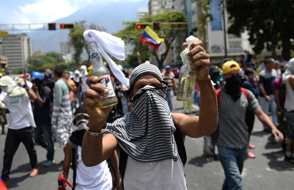 Manifestante de oposição mostra coquetel molotov nesta quinta (1º) — Foto: Matias Delacroix/AFP