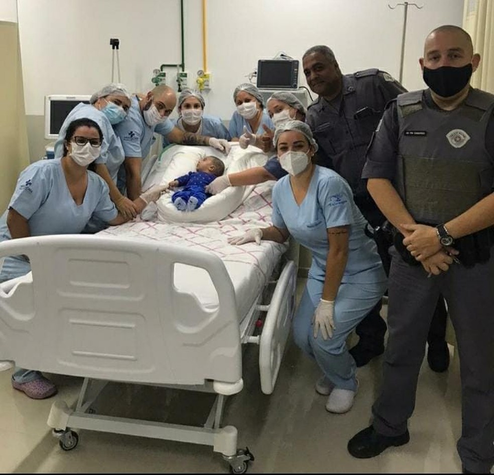 Bebê engasgado é salvo por manobra feita por policiais em Piracaia; equipe da Santa Casa posa com bebê ao lado de policiais responsáveis pela manobra — Foto: Divulgação/ Polícia Militar