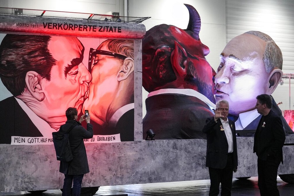 Carro alegório no carnaval da Colônia, na Alemanha, mostrou bonecos de Vladimir Putin e de um diabo se beijando, em alusão à famosa imagem do beijo entre os então líderes da União Soviética, Leonid Brezhnevat, e da Alemanha Oriental, Erich Honecker, em 14 de fevereiro de 2023. — Foto: Martin Meissner/ AP
