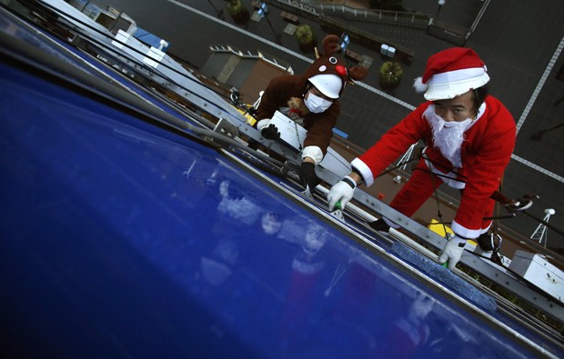 Vestidos de Papai Noel e rena, limpadores de janela participam de evento em shopping em Tóquio, no Japão (Foto: Yuya Shino/Reuters)