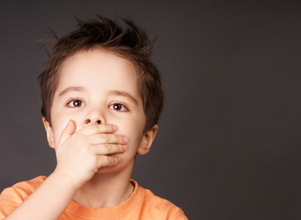 Criança preocupada ou sufocada com a mão na boca (Foto: Shutterstock)