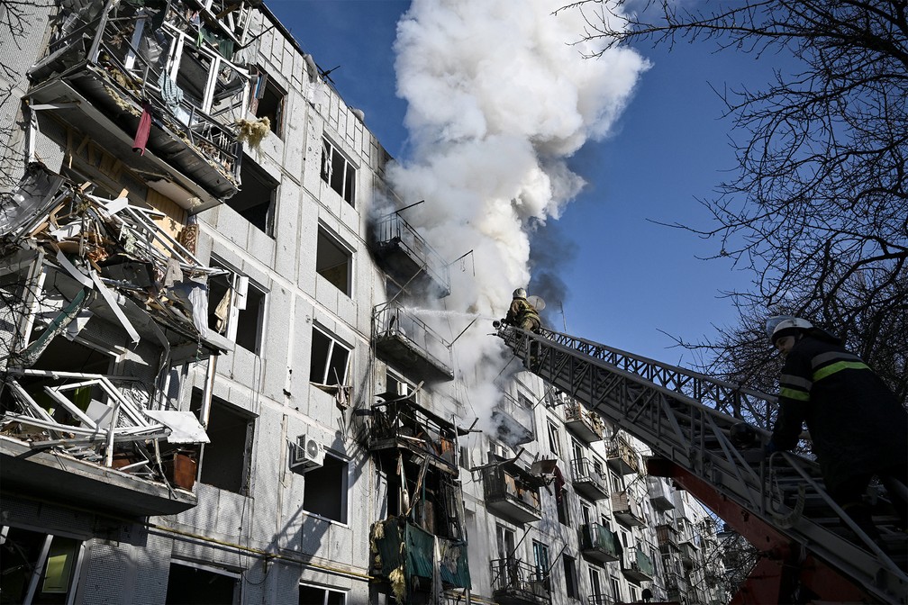 Bombeiros controlam incêndio em um prédio após bombardeios na cidade de Chuguiv, no leste da Ucrânia, em 24 de fevereiro de 2022 — Foto: Aris Messinis/AFP