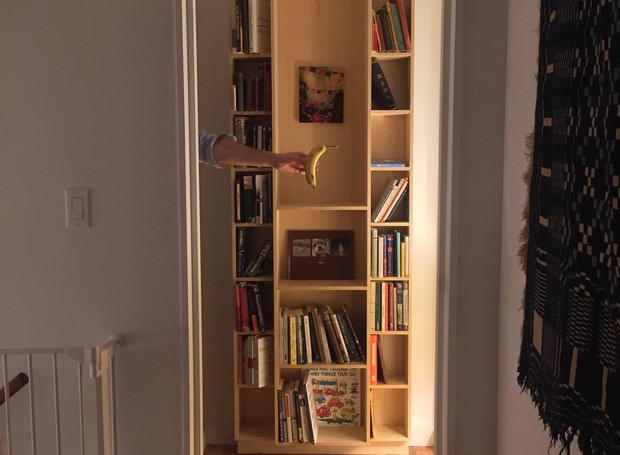 Quando aberta, a porta parece uma estante encostada na parede do corredor. O morador optou por decorar a estante com seus livros e quadros pessoais.   (Foto: Reprodução/ Imgur)