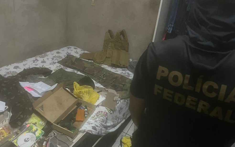 Roupas militares, fuzil e colete em cima da cama do suspeito, em Jataí, Goiás — Foto: Divulgação/Polícia Federal 