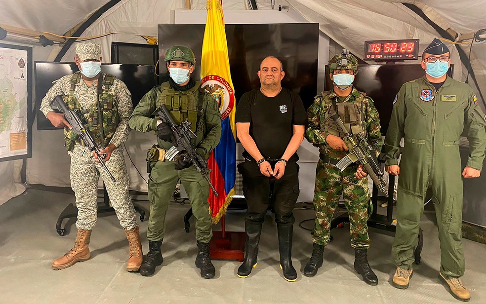 Dairo ‘Otoniel’ Usuga, líder do Clan del Golfo, ao lado de soldados colombianos após ser capturado em Necocli, no sábado (23) — Foto: Colombia's Military Forces/Handout via Reuters