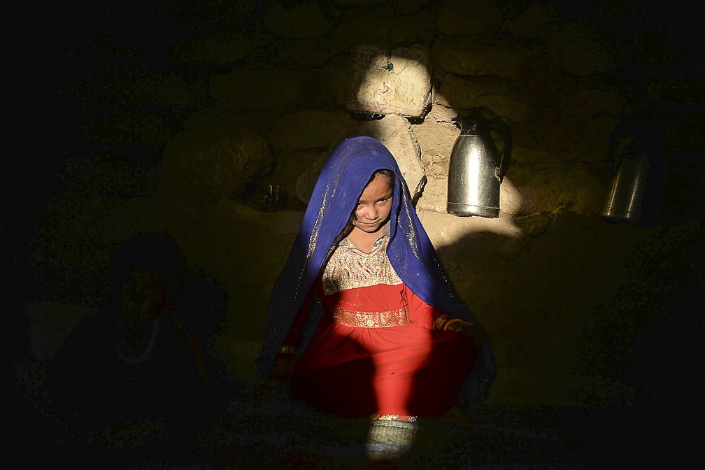 Asho, uma garotinha que ficou noiva de um homem de 23 anos por causa de dívidas da família, é fotografada em 14 de outubro de 2021 no campo de pessoas deslocadas de Shamal Darya, em Qala-i-Naw, capital da província de Badghis. O casamento infantil é praticado há séculos no Afeganistão, mas a guerra, a seca e a pobreza levaram muitas famílias a vender suas filhas cada vez mais cedo. — Foto: Hoshang Hashimi/AFP