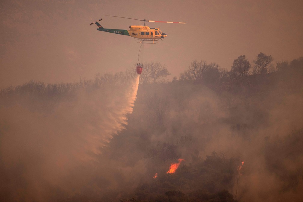 Helicóptero joga água em foco de incêndio na região de Mijas, na província de Málaga, na Espanha. — Foto: Jorge Guerrero/AFP