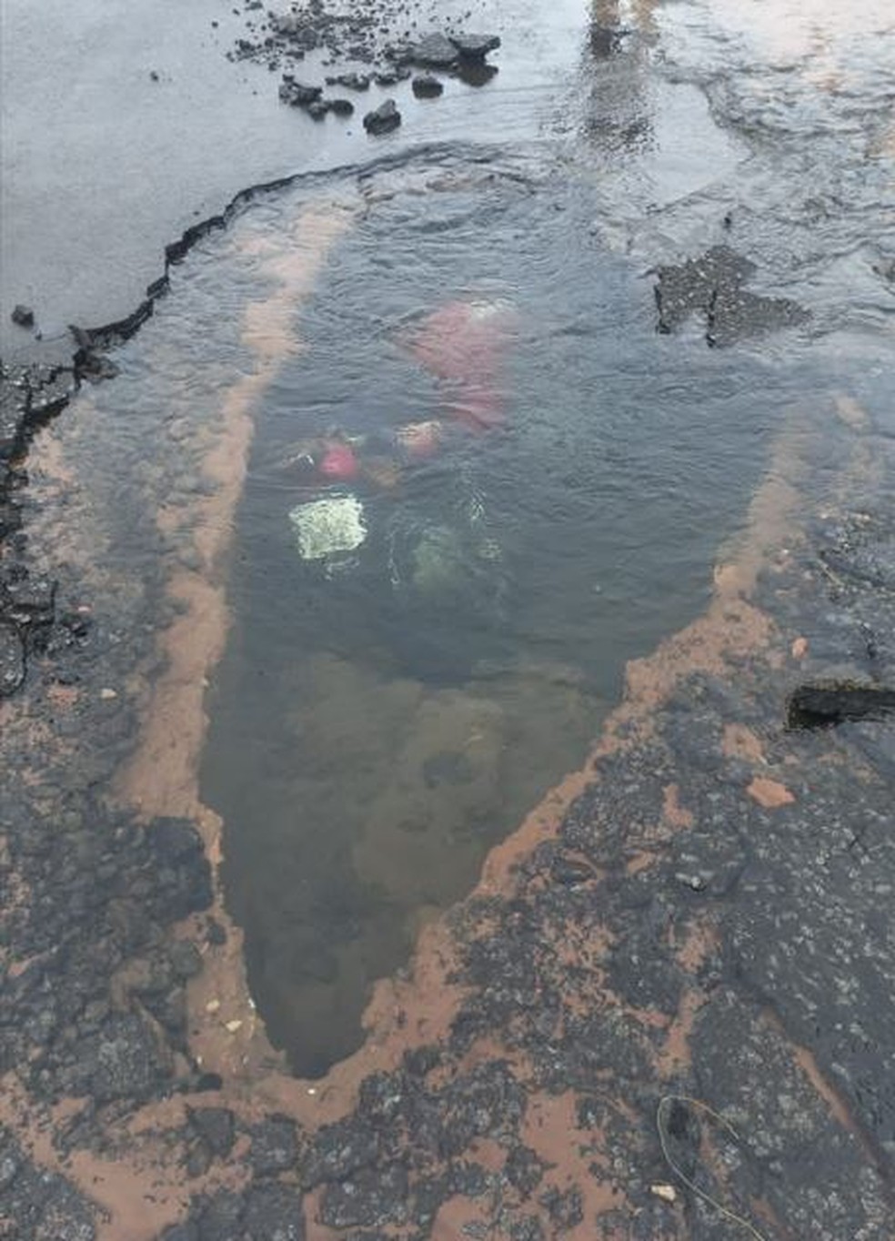 Moto fica submersa após galeria de água romper em Rio Claro e abrir um buraco no asfalto — Foto: Redes sociais