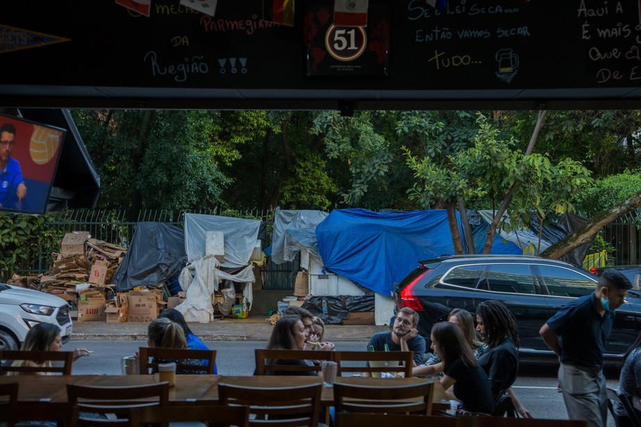 Desigualdade cresce e amplia contrastes sociais: pessoas em situação de vulnerabilidade em frente a restaurante na Av. Paulista, em São Paulo