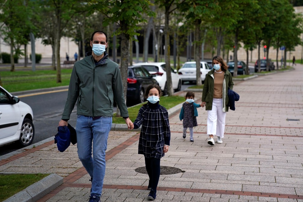 Uma família que usa máscaras protetoras dá um passeio depois que as restrições foram parcialmente levantadas para crianças pela primeira vez em seis semanas, durante o surto da doença por coronavírus em Bilbao, norte da Espanha, neste domingo (26) — Foto: Vincent West/Reuters