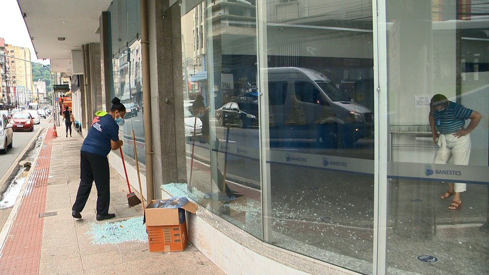 Funcionária limpou estilhaços de vidro de agência bancária quebrada por homem em Vitória  — Foto: Reprodução/TV Gazeta