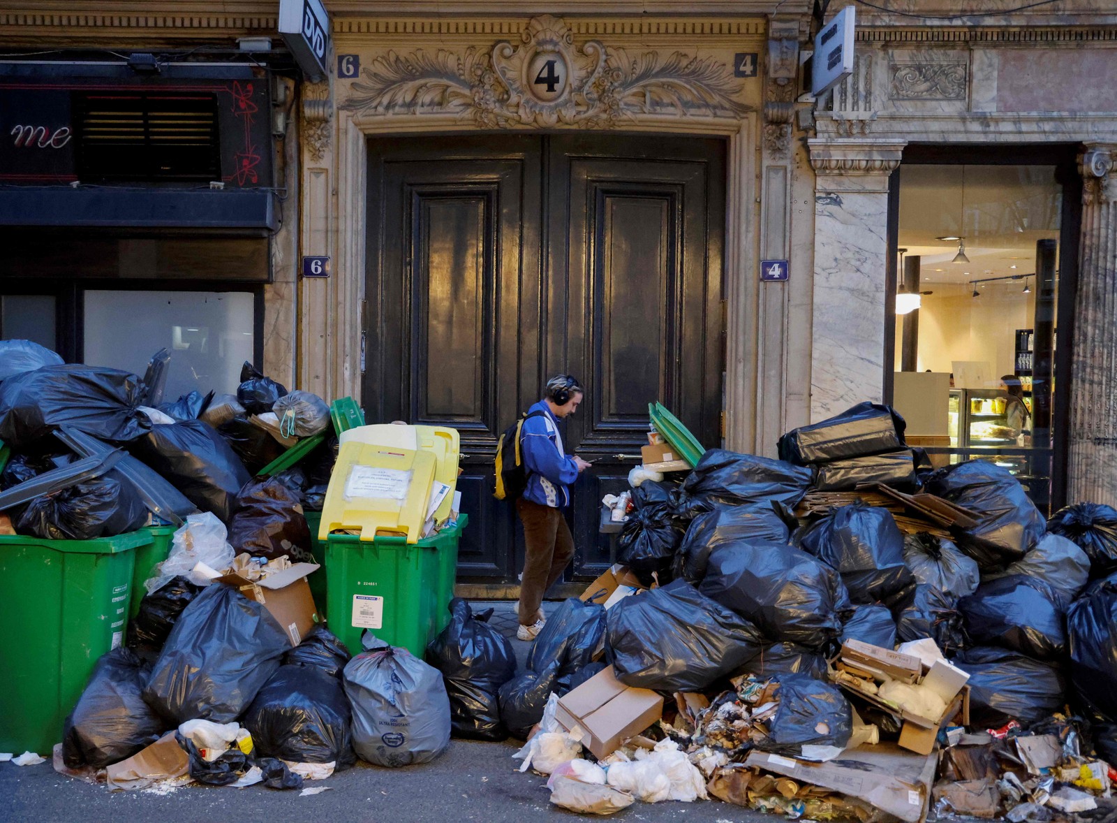 Homem passa por uma pilha de sacos de lixo que se acumulam desde que os coletores de lixo entraram em greve contra a proposta de reforma das pensões do governo francês — Foto: LUDOVIC MARIN/AFP