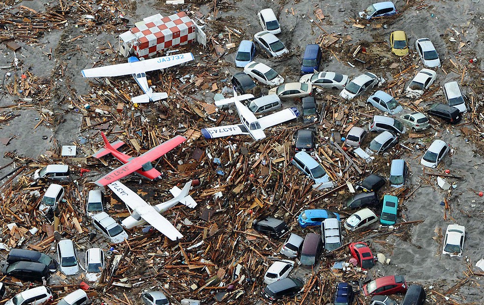 Pequeno aviões e veículos amontoam-se entre os escombros após serem varridos por tsumani que atingiu oJapão, em 2011 — Foto: Kyodo News/AP Photo
