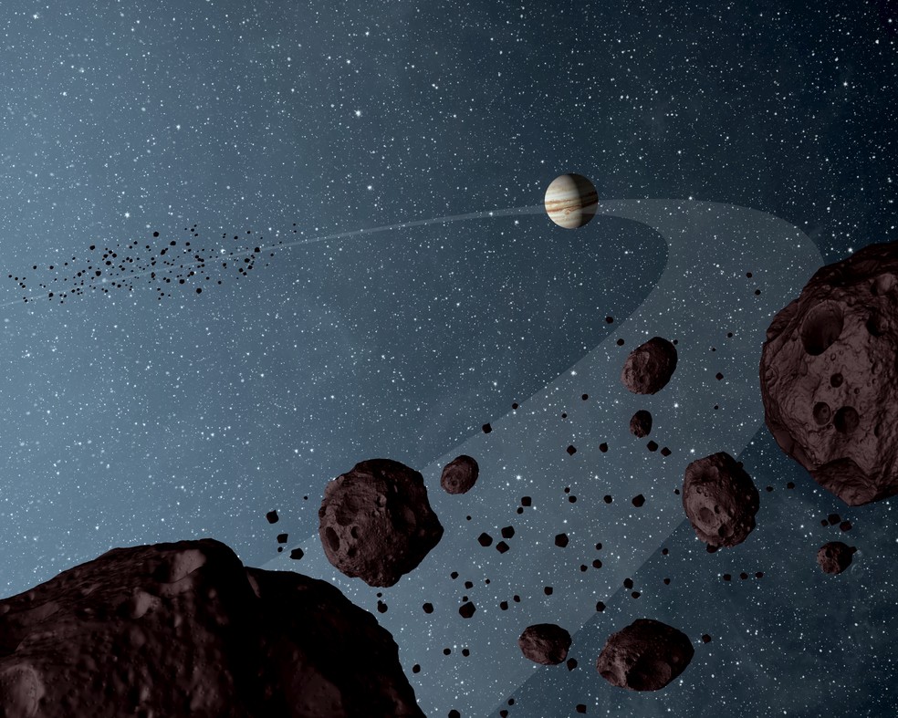 Análises mostraram que os asteróides que seguem o sol na mesma órbita de Júpiter são uniformemente escuros com um toque da cor vinho e têm superfícies foscas que refletem pouca luz solar. — Foto: NASA/JPL-Caltech
