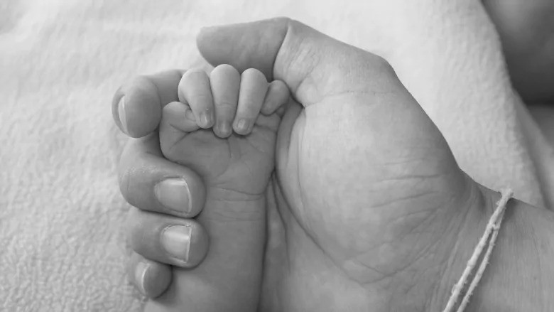 Mãe segurando a mão do filho recém nascido (Foto: Shutterstock)