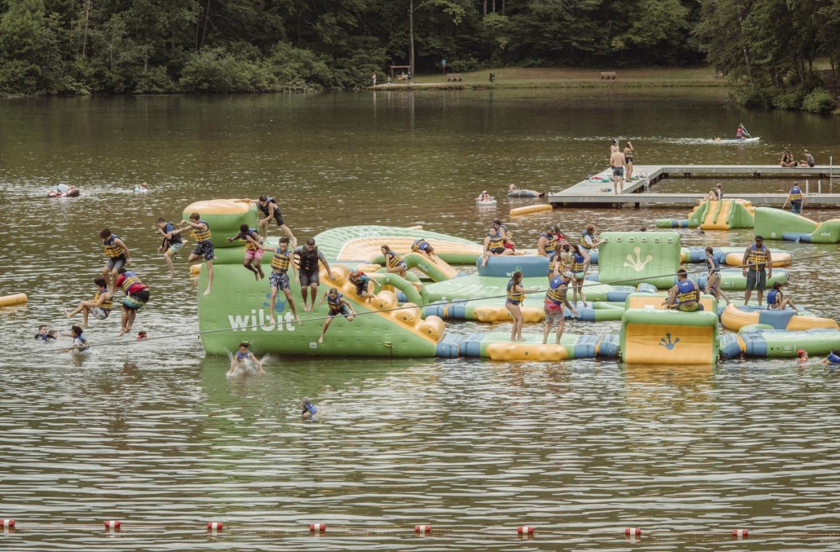 Crianças brincam na pista de obstáculos aquáticos em um lago no Yogi Bear's Jellystone Park, em Bostic, Carolina do Norte — Foto: Mike Belleme/The New York Times