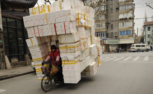 Em 29 de fevereiro deste ano, uma mulher foi flagrada com um triciclo supercarregado com caixas de isopor em uma rua de Xangai, na China. Por conta da quantidade de embalagens, a condutora ficava praticamente escondida no meio, sem visão lateral. (Foto: Peter Parks/AFP)