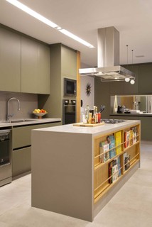 No projeto da arquiteta Bianca da Hora, a cozinha tem ilha de cocção com prateleiras para livros de gastronomia, além de uma bancada espaçosa
