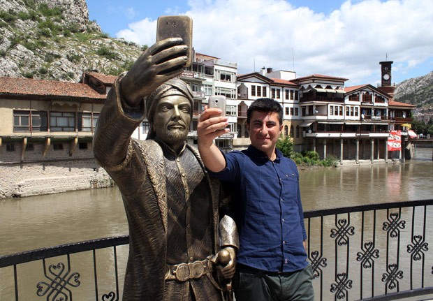 Turista faz selfie ao lado da estátua antes de ela ser alvo de vândalos (Foto: AP)