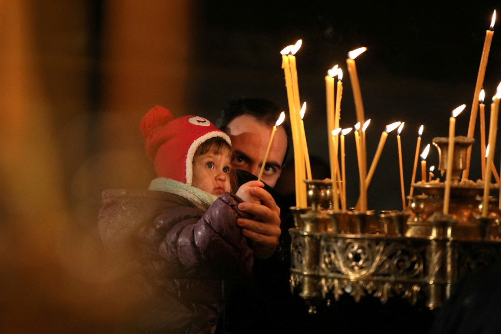 Homem segura seu filho enquanto participam da missa de Natal na catedral Alexander Nevski, em Sofia, Bulgária, neste sábado (25) — Foto: Spasiyana Sergieva/Reuters