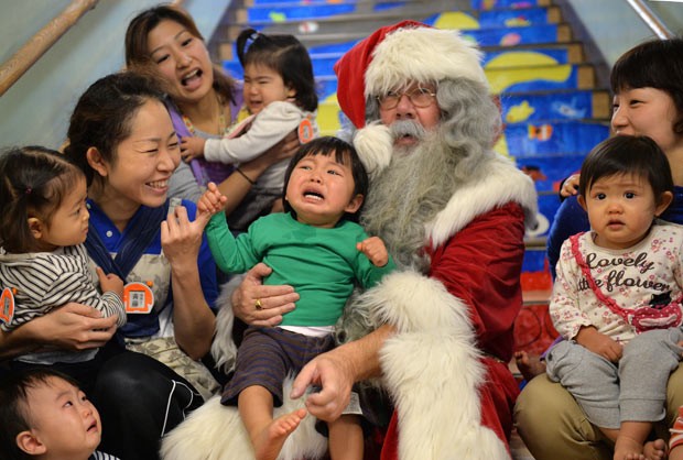 Crianças posam com Papai Noel nesta segunda-feira (9) em Tóquio (Foto: Yoshikazu Tsuno/AFP)