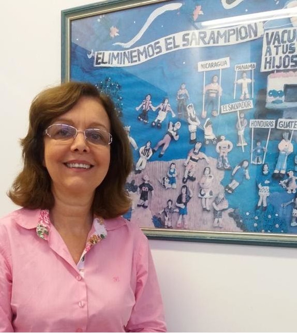 Marilda com quadro da campanha contra sarampo que fica em sua sala: 'Brasil foi luz no fim do túnel para outros países' — Foto: Vinicius Ferreira/IOC/Fiocruz/Via BBC