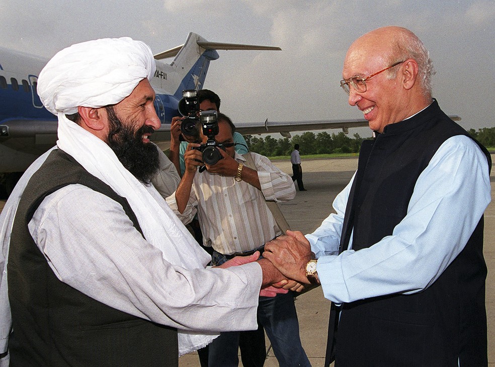Mohammad Hasan Akhund (à esquerda), então vice-ministro das Relações Exteriores do Afeganistão, cumprimenta seu homólogo paquistanês, Sartaj Aziz, em uma base aérea em Rawalpindi, a cerca de 25 km de Islamabad, em foto de 25 de agosto de 1999  — Foto: Saeed Khan/AFP