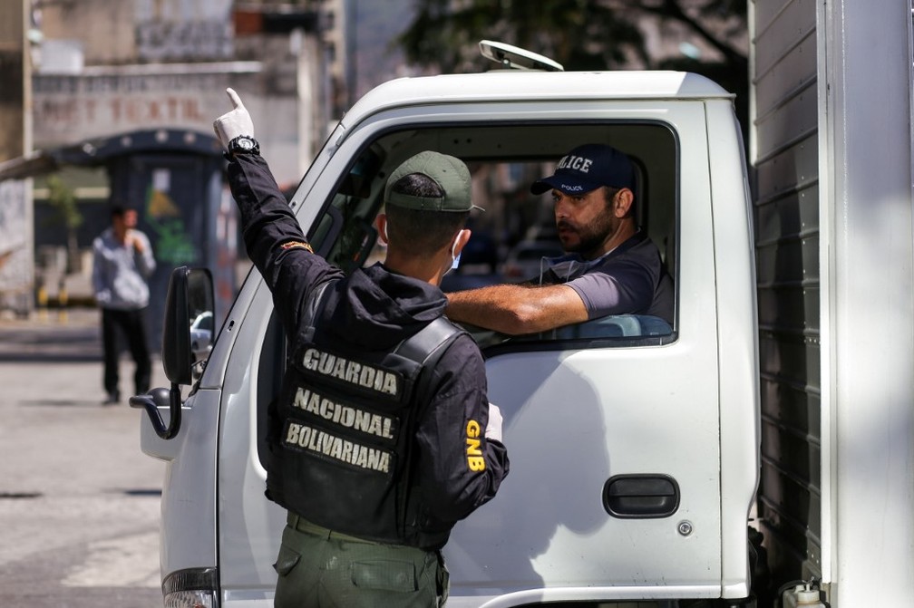 Guarda venezuelano dá instruções a motorista de caminhão em Caracas, em 17 de março de 2020 — Foto: Cristian Hernandez / AFP