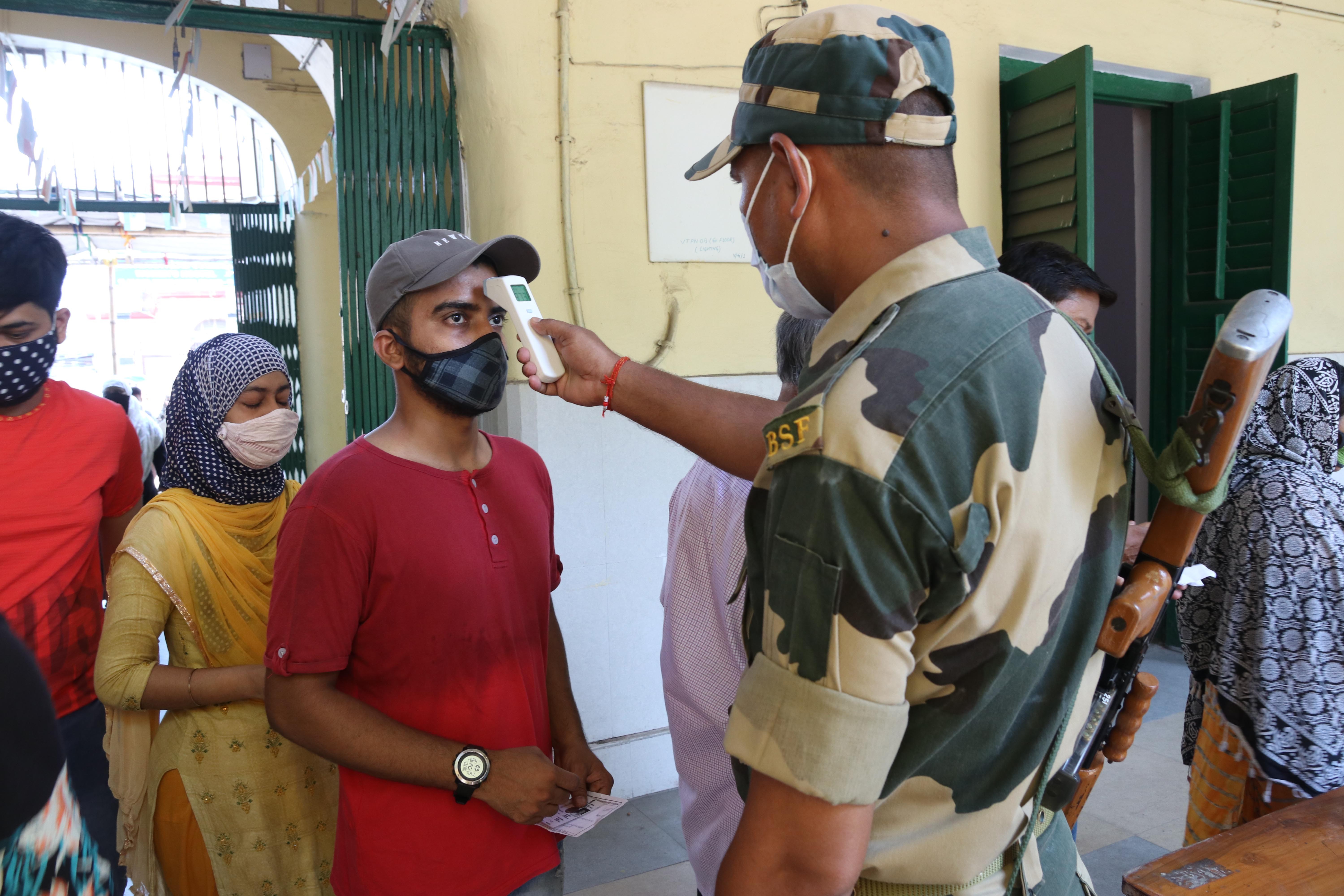 A paramilitary personnel  checks the body temperature of a woman wearing mask shows before her vote at a polling station during  8th phase of West Bengal assembly elections in Kolkata, India on 29 th April, 2021. The 8th phase of West Bengal Assembly Elec (Foto: NurPhoto via Getty Images)