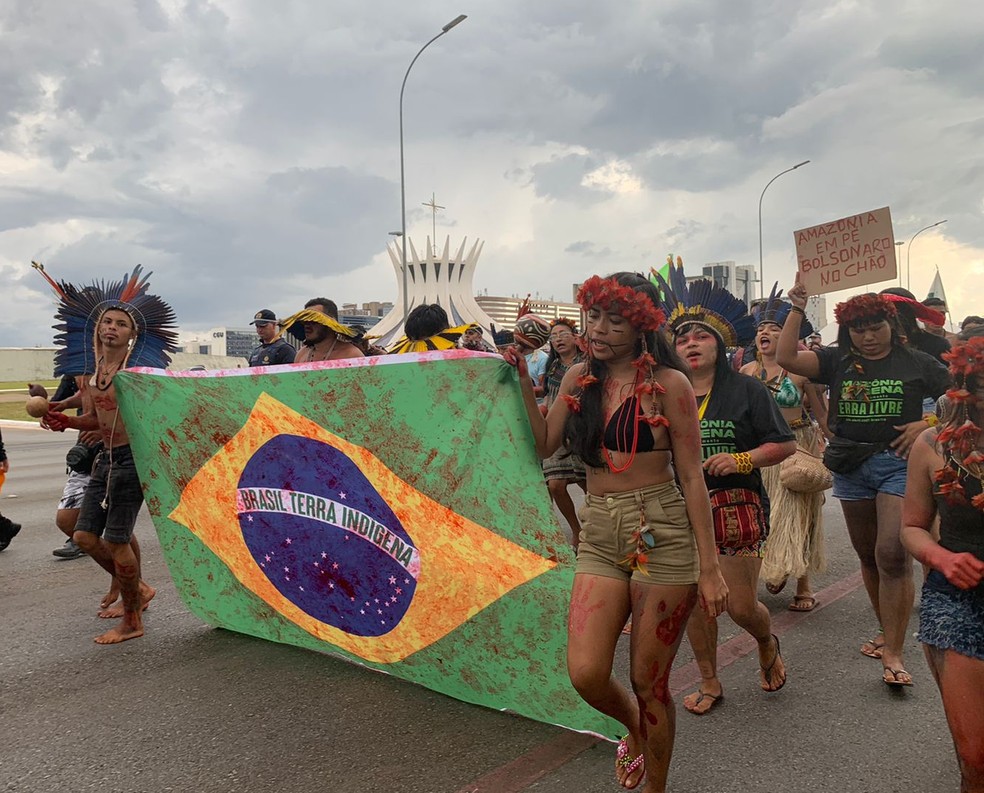 Em protesto, indígenas carregam uma bandeira do Brasil com manchas vermelhas simbolizando sangue, em Brasília — Foto: Foto: Amanda Sales/ g1
