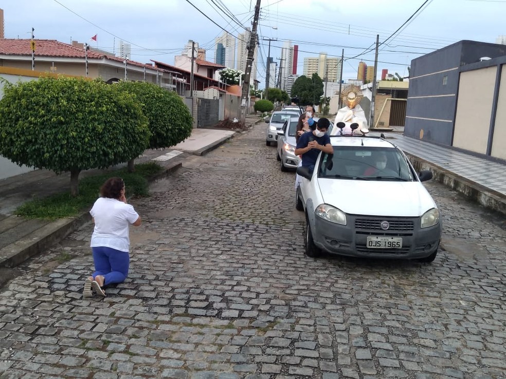 Mulher se ajoelha durante durante "celebração ambulante" no bairro Ponta Negra, em Natal — Foto: Marcos Figueiredo