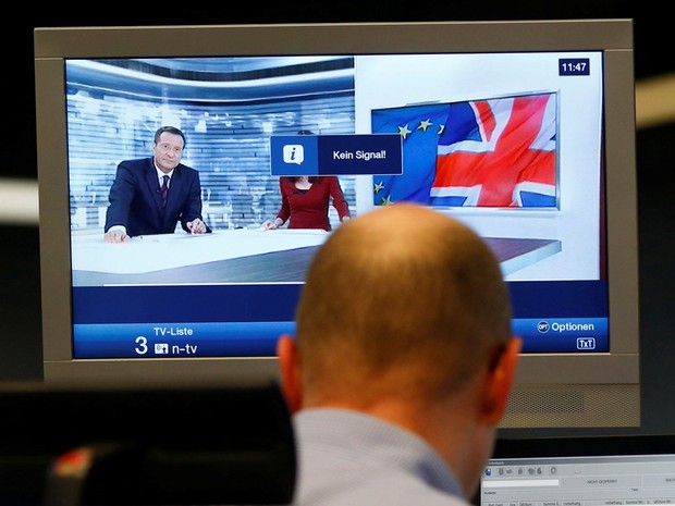 Comerciante trabalha em frente a um noticiário de uma televisão na bolsa de Frankfurt, na Alemanha (Foto: Ralph Orlowski/ Reuters)