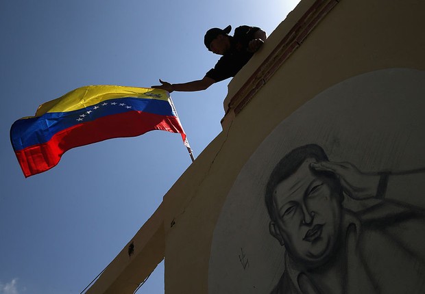Bandeira da Venezuela sobre muro com rosto de Hugo Chávez (Foto: John Moore/Getty Images)