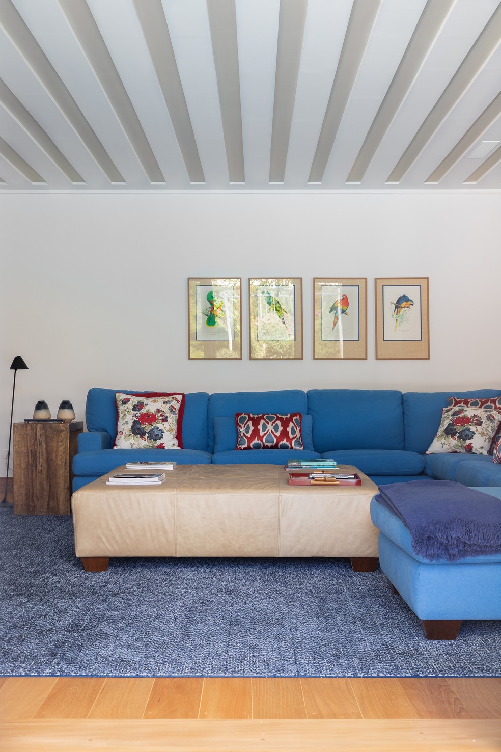 Neste canto do living integrado, um tom alegre de azul cobre o estofado do sofá e aparece também no tapete — Foto: Daniela Magario
