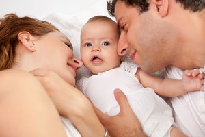 Casal deitado com o bebê (Foto: Shutterstock)