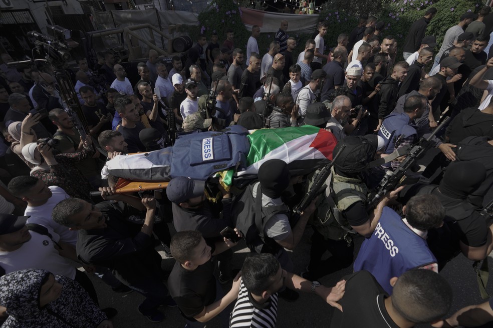 Palestinos carregam o corpo da jornalista Shireen Abu Akleh, da Al Jazeera, com o colete de imprensa sobre o caixão — Foto: Majdi Mohammed/AP Photo