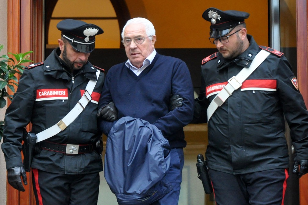 O mafioso Settimino Mineo é levado pela polícia ao sair de delegacia após sua prisão nesta terça (4), em Palermo, na Itália — Foto: Alessandro Fucarini/AFP