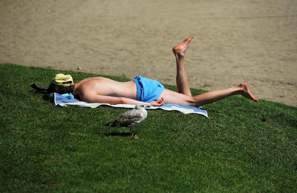Homem deitado ao Sol na praia La Malagueta, na Espanha — Foto: Jon Nazca/Reuters