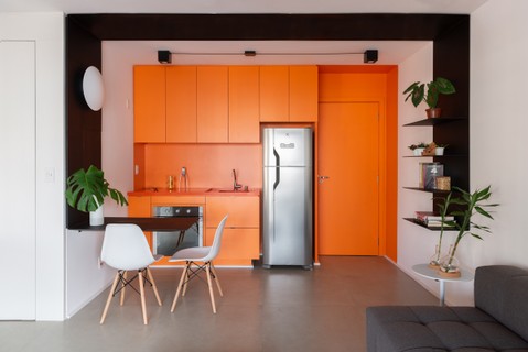 Na cozinha, um grande bloco de Formica laranja forma os armários e a bancada. As peças foram desenhadas pelo escritório CR2 Arquitetura e executadas pela Marcenaria Padrão