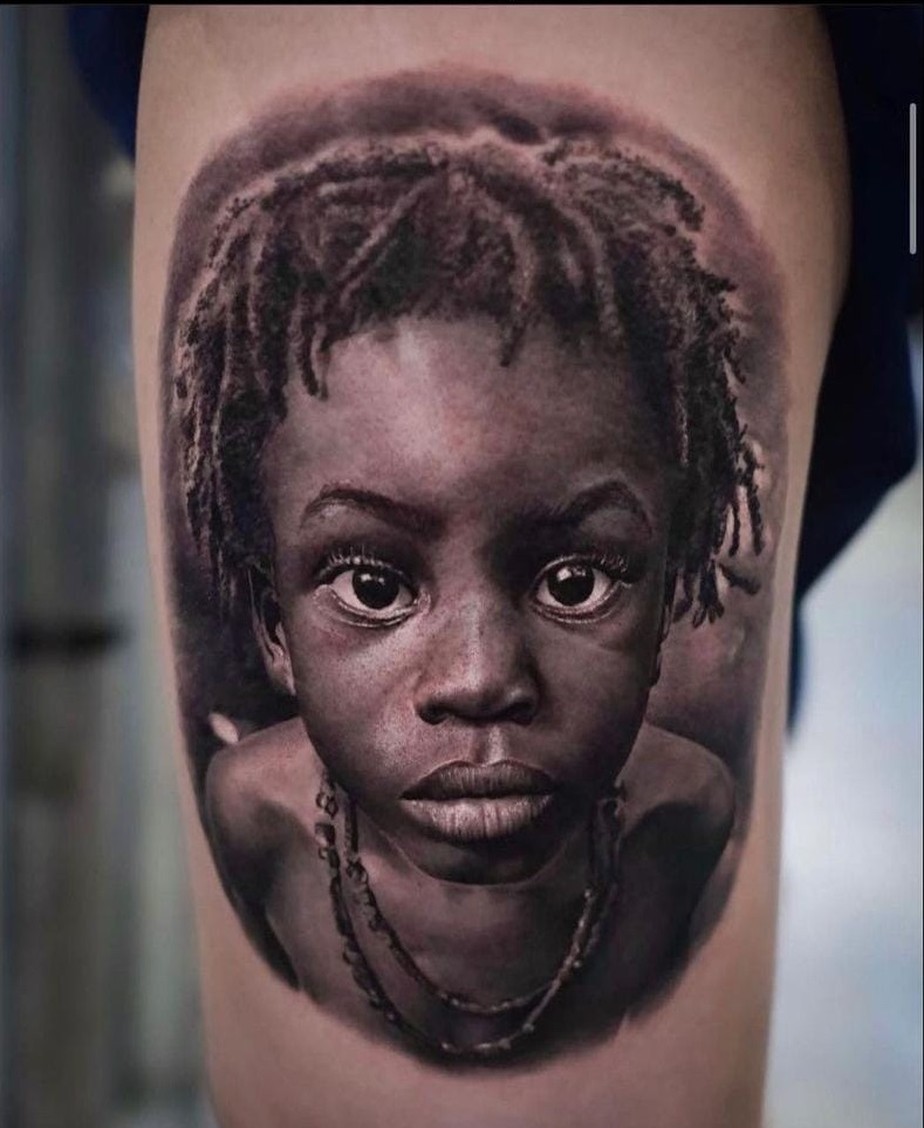 O menino Ayo, de 4 anos, teve o rosto tatuado no braço de um homem branco. Tatuagem foi premiada em competição
