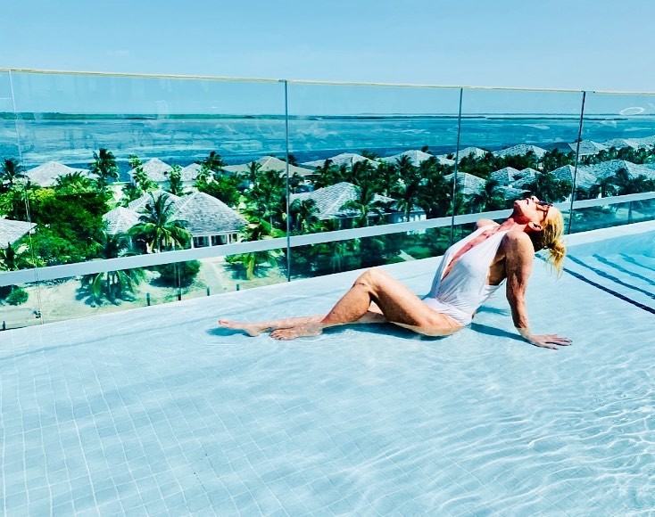 Mãe de Danielle Winits aposa em maiô branco decotado em piscina com bela paisagem  (Foto: Reprodução/Instagram)