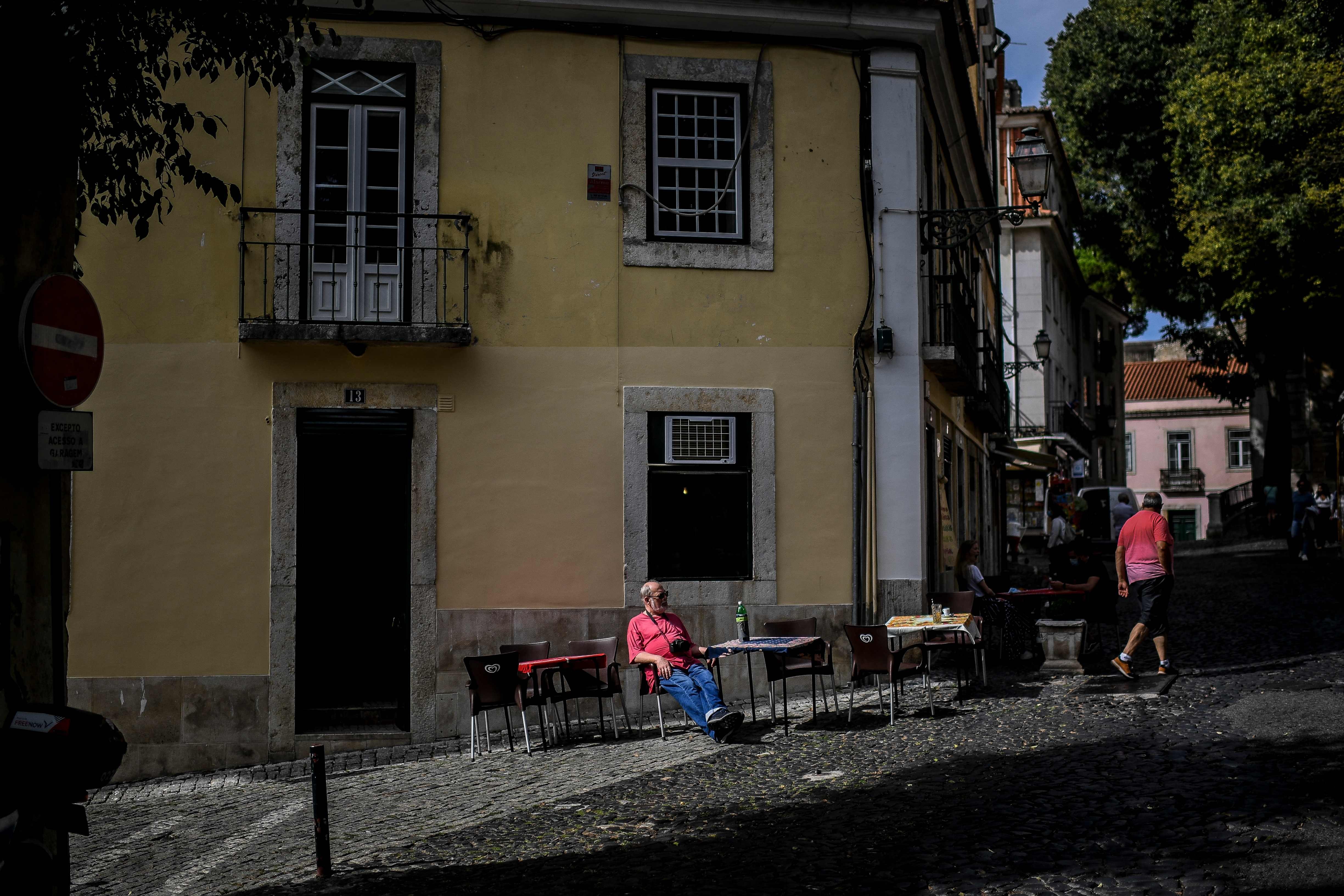 Cliente na mesa instalada na calçada de um bar em Alfama, Lisboa