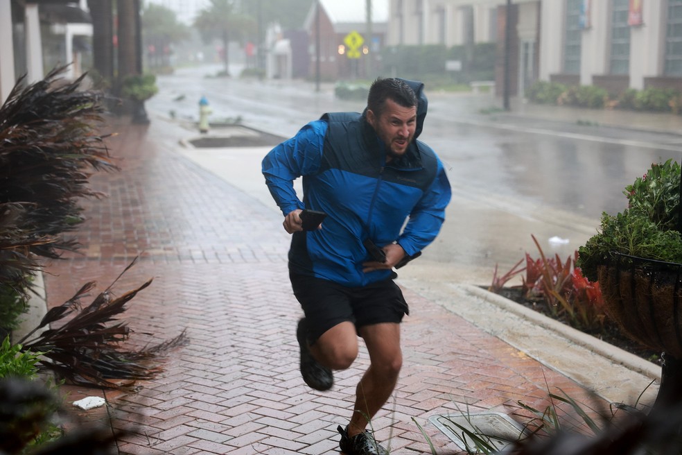 Morador se esforça para correr contra o vento até um abrigo, em Sarasota — Foto: Joe Raedle/Getty Images/AFP