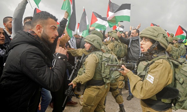 Um palestino discute com um soldado israelense durante um protesto do Vale do Jordão após o anúncio do plano de paz de Donald Trump