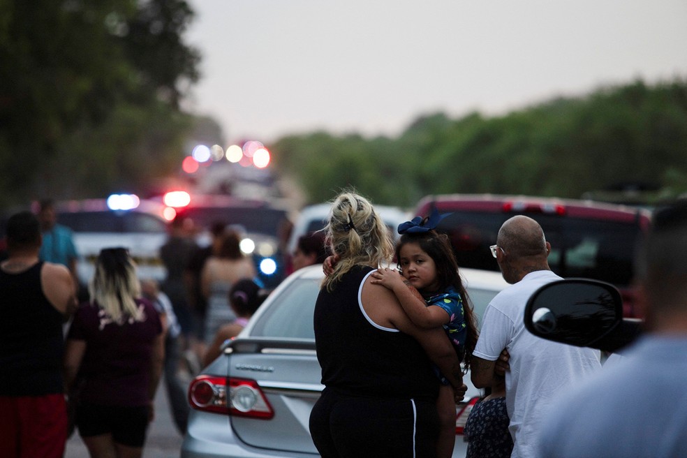 Mãe e filha se abraçam observando local onde pessoas foram achadas mortas dentro de um caminhão em San Antonio, Texas (EUA), na segunda-feira (27) — Foto: Kaylee Greenlee Beal/Reuters