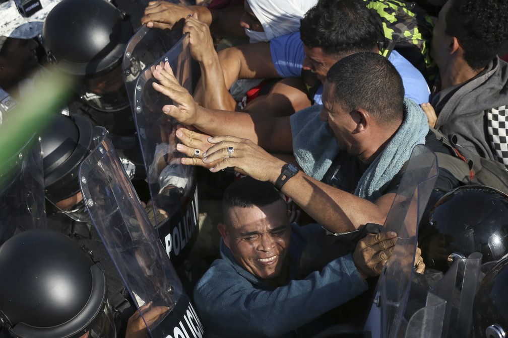 Cordão humano de policiais mexicanos tenta conter neste sábado (18) milhares de migrantes de caravana de países que deixaram a América Central — Foto: Marco Ugarte/AP Photo